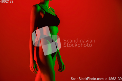 Image of Beautiful female model on orange background in neon light. Beauty, cosmetics, spa, depilation, diet and treatment, fitness concept.