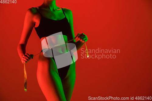 Image of Beautiful female model on orange background in neon light. Beauty, cosmetics, spa, depilation, diet and treatment, fitness concept.