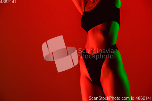 Image of Beautiful female model on orange background in neon light. Beauty, cosmetics, spa, depilation, diet and treatment, fitness concept.