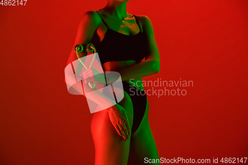 Image of Beautiful female model on orange background in neon light. Beauty, cosmetics, spa, depilation, diet and treatment, fitness concept.