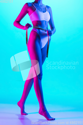 Image of Beautiful female body on blue background in purple neon light. Beauty, cosmetics, spa, depilation, diet and treatment, fitness concept.