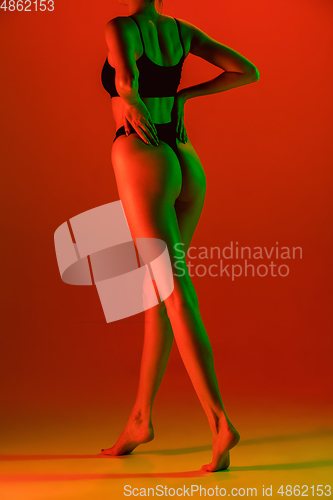 Image of Beautiful female model on orange background in neon light. Beauty, cosmetics, spa, depilation, diet and treatment, fitness concept.