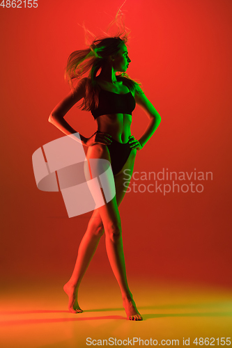 Image of Beautiful female model on orange background in neon light. Beauty, cosmetics, spa, depilation, diet and treatment, fitness concept.