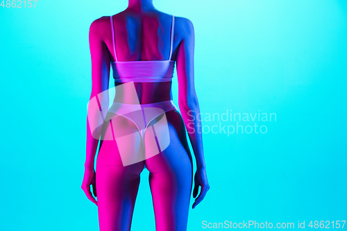 Image of Beautiful female body on blue background in purple neon light. Beauty, cosmetics, spa, depilation, diet and treatment, fitness concept.