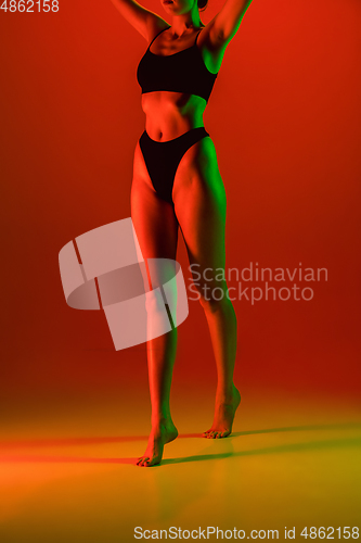 Image of Beautiful female model on orange background in neon light. Beauty, cosmetics, spa, depilation, diet and treatment, fitness concept.