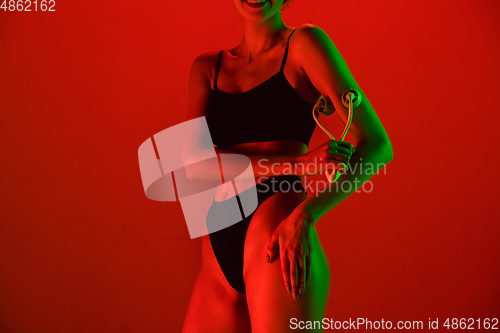 Image of Beautiful female model on orange background in neon light. Beauty, cosmetics, spa, depilation, diet and treatment, fitness concept.