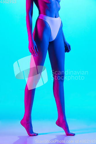 Image of Beautiful female body on blue background in purple neon light. Beauty, cosmetics, spa, depilation, diet and treatment, fitness concept.