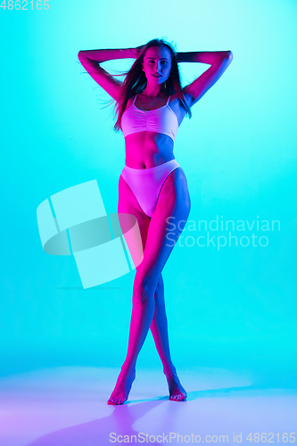 Image of Beautiful female body on blue background in purple neon light. Beauty, cosmetics, spa, depilation, diet and treatment, fitness concept.