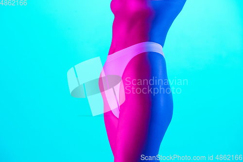 Image of Beautiful female body on blue background in purple neon light. Beauty, cosmetics, spa, depilation, diet and treatment, fitness concept.