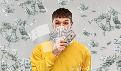 Image of happy young man in yellow sweatshirt with money