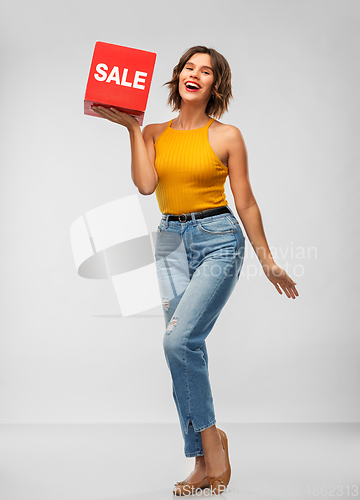 Image of happy smiling young woman posing with sale sign