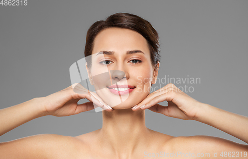 Image of beautiful young woman touching her face and chin