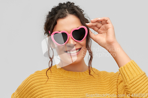 Image of smiling young woman in heart-shaped sunglasses