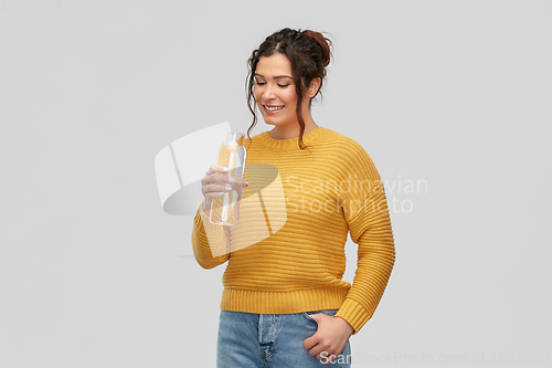 Image of smiling young woman with water in glass bottle