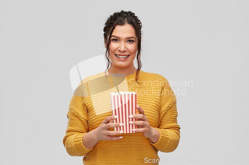 Image of happy smiling young woman with bucket of popcorn