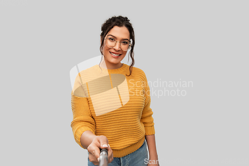 Image of smiling woman taking picture with selfie stick