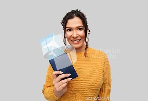 Image of smiling young woman with passport and air ticket