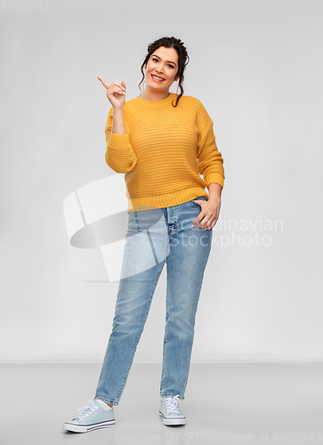 Image of happy smiling young woman pointing finger up