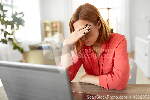 Image of stressed woman with laptop working at home office