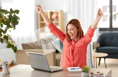 Image of happy woman with laptop working at home office