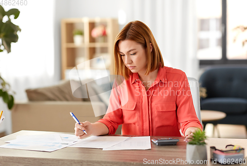 Image of woman with calculator and papers working at home