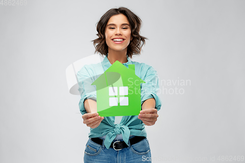 Image of smiling young woman holding green house