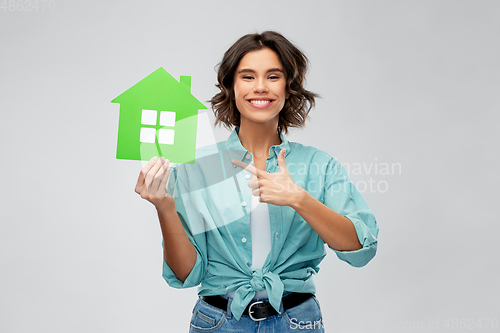 Image of smiling young woman showing green house