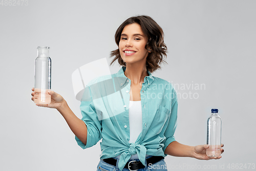 Image of smiling young woman comparing bottles of water