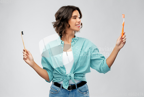 Image of woman comparing wooden and plastic toothbrush