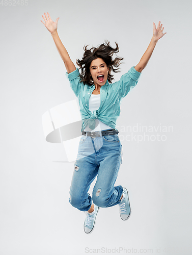 Image of happy young woman jumping over grey background