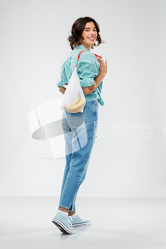 Image of happy woman with bananas in reusable string bag