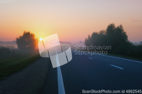 Image of Car Drives On The Suburban Road On A Foggy Morning During Sunrise