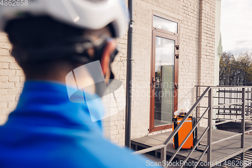 Image of Contacless delivery service during quarantine. Man delivers food and shopping bags during isolation