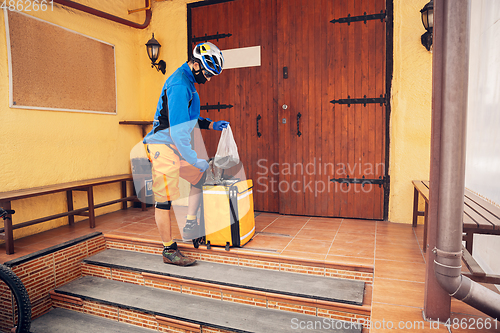 Image of Contacless delivery service during quarantine. Man delivers food and shopping bags during isolation