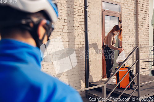 Image of Contacless delivery service during quarantine. Man delivers food and shopping bags during isolation