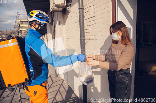 Image of Contacless delivery service during quarantine. Man delivers food and shopping bags during isolation