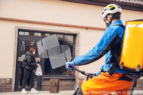 Image of Contacless delivery service during quarantine. Man delivers food and shopping bags during isolation