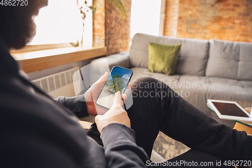 Image of Young man using gadgets to watch cinema, photos, online courses, taking selfie or vlog, online shopping