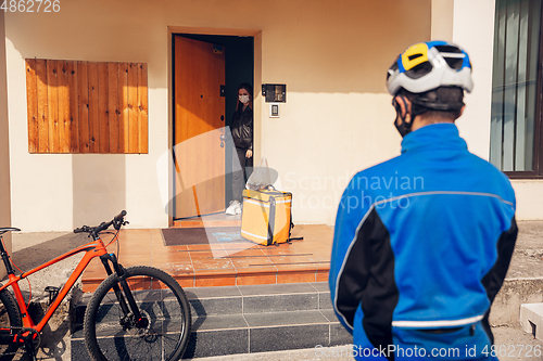 Image of Contacless delivery service during quarantine. Man delivers food and shopping bags during isolation