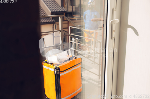 Image of Contacless delivery service during quarantine. Man delivers food and shopping bags during isolation