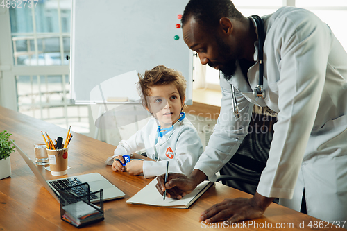 Image of Little caucasian boy as a doctor consulting for patient, working in cabinet, close up