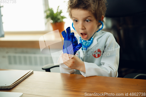 Image of Little caucasian boy as a doctor consulting for patient, working in cabinet, close up