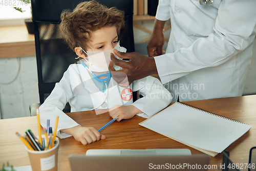 Image of Little caucasian boy as a doctor consulting for patient, working in cabinet, close up