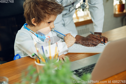 Image of Little caucasian boy as a doctor consulting for patient, working in cabinet, close up