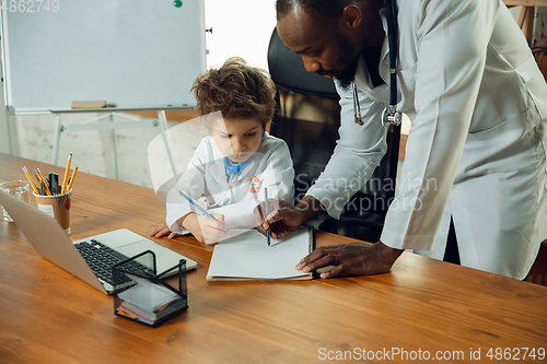 Image of Little caucasian boy as a doctor consulting for patient, working in cabinet, close up