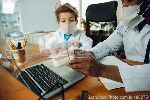 Image of Little caucasian boy as a doctor consulting for patient, working in cabinet, close up