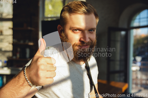 Image of Caucasian musician playing guitar during online concert at home isolated and quarantined, thumb up, nice