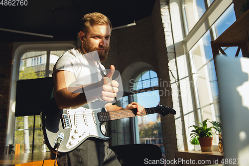 Image of Caucasian musician playing guitar during online concert at home isolated and quarantined, thumb up, nice