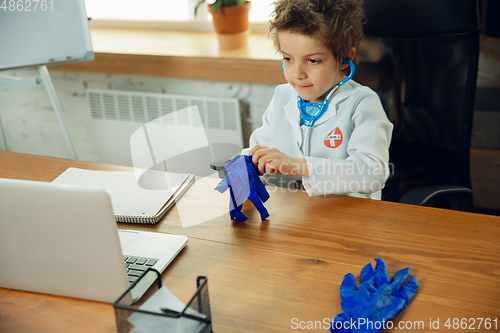 Image of Little caucasian boy as a doctor consulting for patient, working in cabinet, close up