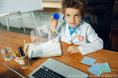 Image of Little caucasian boy as a doctor consulting for patient, working in cabinet, close up